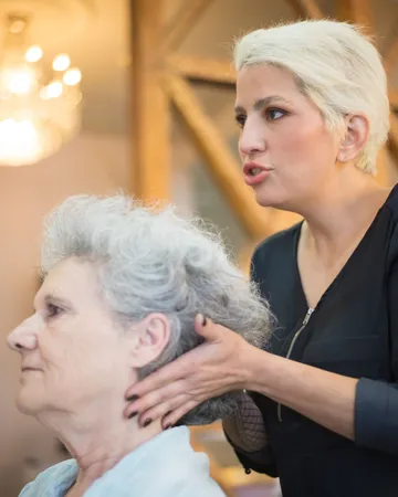 Uploaded photo, portrait: a hairdresser with short blonde hair setting an older woman’s grey curls.