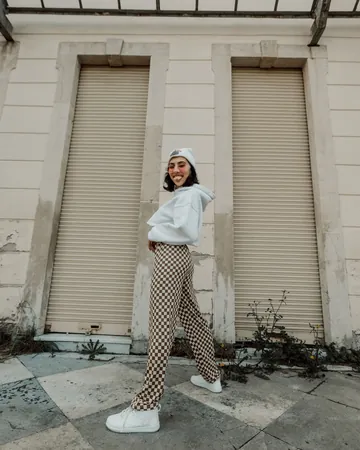 Sample ad for a clothing shop: a woman in a white hoodie and checked trousers on a city street.